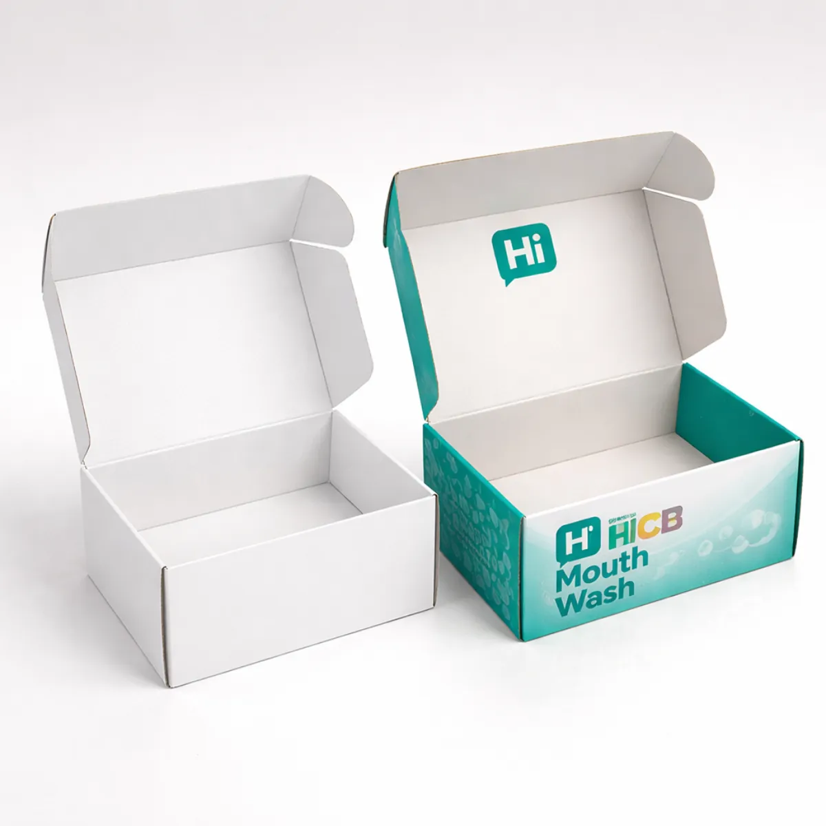 Two open cardboard mailer boxes- one plain white and one with teal mouthwash branding- class=